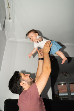Man Lifts Baby in Living Room During Daytime