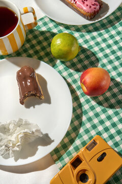 Summer breakfast picnic table with eclairs, colorful fruit and camera