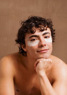 Man With Eye Patches Smiles While Resting His Chin on His Hand