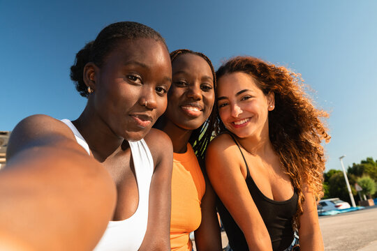 Three Female Friends Smiling Together in Sunny Outdoor Setting. Selfie