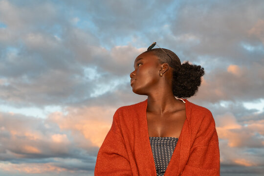 Woman Wearing Red Sweater Looks Away in a Cloudy Sky at Sunset