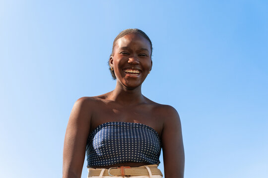 Smiling Woman Stands Outdoors Under Clear Blue Sky. Copy space