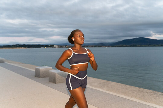 A woman running down the street at sunset along the coast