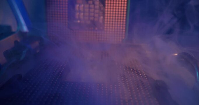 Slow motion insertion of computer processor chip into motherboard socket on electronics lab bench with heatsink and tool.