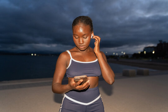 A woman checks the phone and earphones on the street. Ready to run