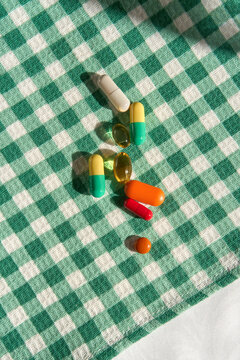 Colorful Vitamins and Dietary Supplements on Green Gingham Tablecloth