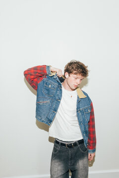 Young man putting on denim jacket with direct flash