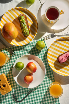 Summer breakfast picnic table with eclairs, colorful fruit and camera