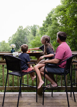 Father and Children Sharing a Quiet Moment on a Porch Overlooking the 