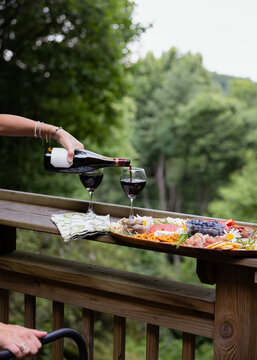 Woman pouring a glass of wine with charcuterie board. 