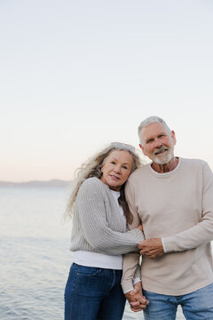 Senior couple holding hands on beach, candid affectionate moment