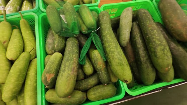 Fresh winter melon and bottle gourd varieties displayed in green baskets at a produce market, offering healthy and organic vegetable options for nutritious cooking and seasonal eating