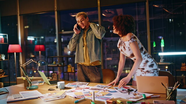 Coworkers celebrating good news on phone call in design office at night teamwork
