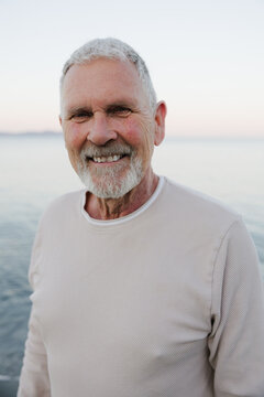 Smiling senior man by the sea: candid portrait of relaxed retire