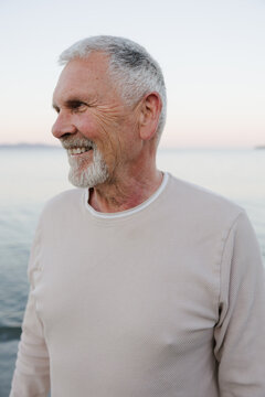 Candid portrait of a happy senior man smiling by the beach