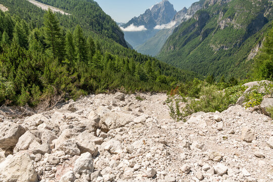 Taibon Agordino, Italy. Dry mountain riverbed with limestone debris and Dolomite valley landscape