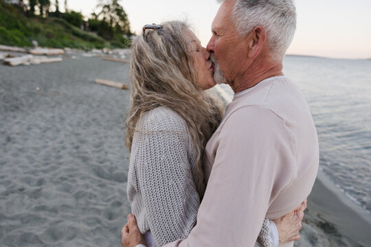 Elderly couple sharing a tender kiss on a quiet beach