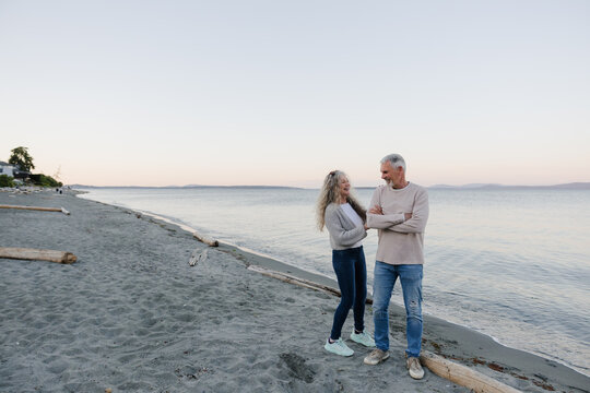 Candid senior couple laughing together on a peaceful beach at su
