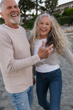 Happy senior couple laughing together on beach, candid joyful mo