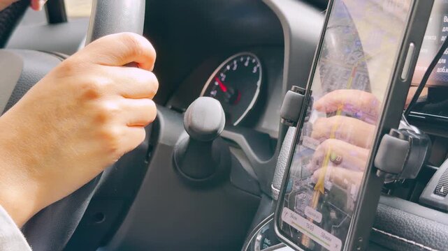 A driver holds the steering wheel while navigating with a phone GPS app inside a moving car in Saint Petersburg. This focused journey evokes a feeling of alert concentration and purposeful travel.