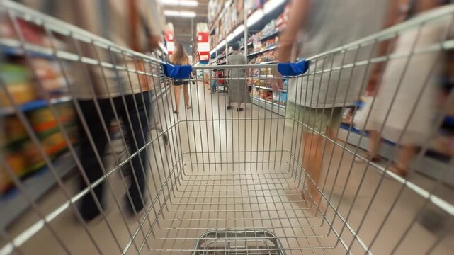 Shopping cart view moving through a supermarket aisle, following a woman customer, capturing the dynamic experience of grocery shopping, fast paced retail environment, and consumer journey