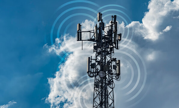 Cell tower with multiple antennas broadcasting signal waves. Dramatic blue sky with clouds. Ideal for telecom, wireless network, and mobile technology editorial or marketing content.