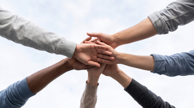 Diverse team stacking hands together in unity, teamwork, collaboration and community support concept on bright background.