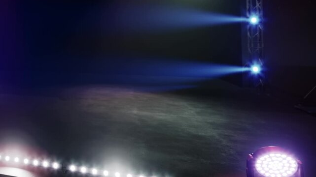 The stage is set with colorful lights in a dark space. The floor is visible with lighting equipment positioned around. This is likely before a performance or show.