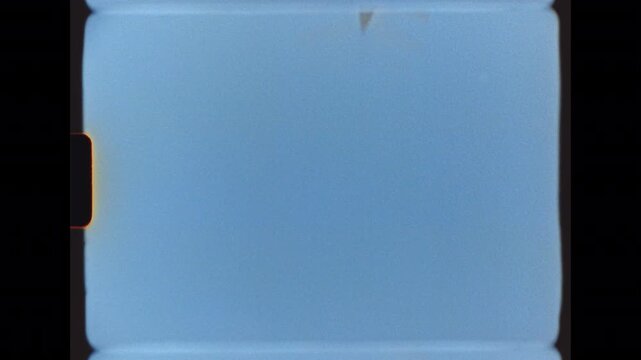 Commercial passenger jet plane flies directly overhead against a clear blue sky, filmed on Super 8 film