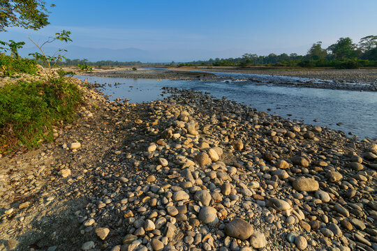 Murti river in the morning, riverbed in foreground with flowing water and stones. Scenic beauty of Dooars landscape, West Bengal, India. Dooars is popular tourist destination for natural landscapes.