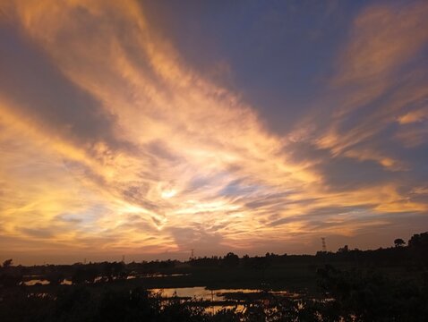 Sunset Over City Skyline with Dramatic Orange Clouds, Glowing Sun, Colorful Evening Sky, Beautiful Horizon and Silhouetted Urban Landscape at Dusk