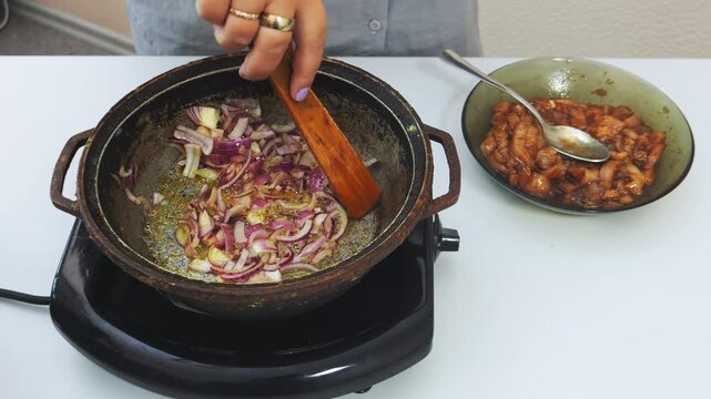 Onions are fried in vegetable oil in a deep cast-iron skillet and stirred