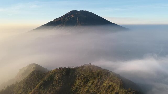 Aerial view of Mount Merbabu, Indonesian volcano rising above thick mist at sunrise