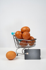 Eggs in shopping cart with credit card symbolizing increasing food prices and grocery inflation © Alberto