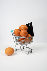 Shopping cart full of eggs with a credit card, symbolizing rising food costs and inflation in grocery shopping © Alberto