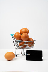 Eggs in shopping cart with credit card, symbolizing rising food costs, inflation, and grocery expenses © Alberto