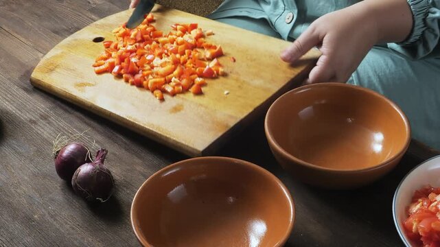 Red peppers are sliced with a knife on a cutting board on the table