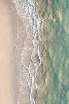 Aerial view of Cape Tribulation beach with gentle waves washing onto the sandy shore and turquoise water in Daintree, Queensland, Australia.