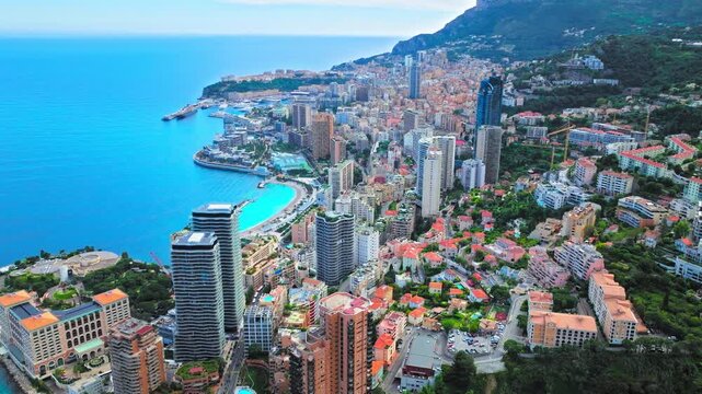 Drone view of Monte Carlo and Monaco&rsquo;s coastline. Dense city buildings, harbour areas, turquoise sea and mountain backdrop create an iconic Mediterranean travel view.