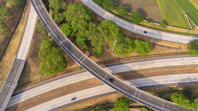Aerial view of a highway interchange with multi-level roads, green trees, and agricultural fields in Central Java, Indonesia.