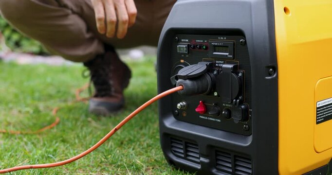 Man starting portable inverter generator for home backup power or outdoor electricity supply