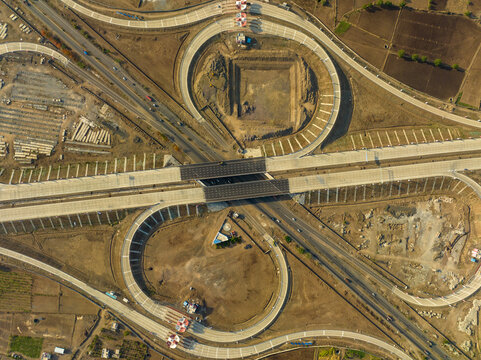 Aerial view of the Sinnar Interchange featuring complex highway curves and concrete roads set within a dry landscape in Sinnar, Maharashtra, India.