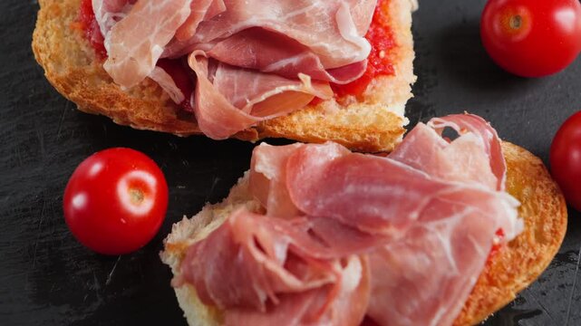 Traditional Spanish breakfast with two slices of pan con tomate topped with Iberian jamon, served as a simple Mediterranean meal. High quality 4k footage