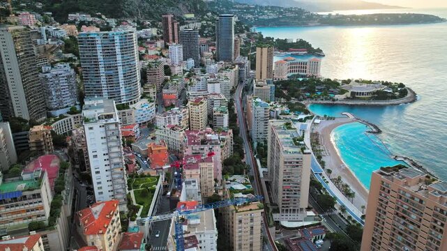 Drone view over Monaco and Monte Carlo. Modern towers, narrow city streets, marina views and blue Mediterranean water create a dramatic urban coastline.