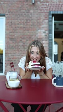 Vertical screen woman excitedly holds cake after giving in to sweet cravings showing the joy and temptation behind breaking strict food rules and dietary restrictions now