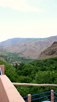Marrakech, morocco. August 9, 2026. Scenic view from a traditional riad terrace overlooking a lush green valley and a berber village nestled in the arid atlas mountains of morocco