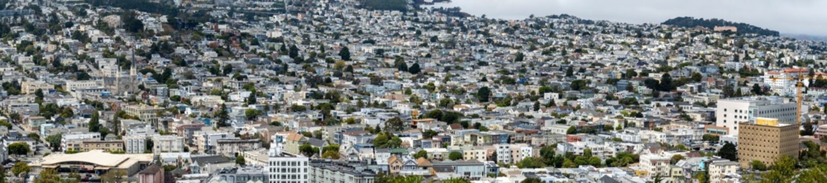 San Francisco-A sweeping panoramic view captures a dense urban landscape filled with tightly packed residential buildings stretching across rolling hills.