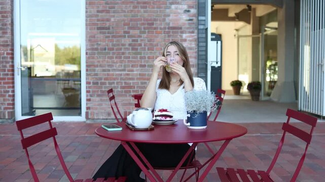 Woman on diet enjoys unsweetened tea at outdoor cafe while leaving cake untouched feeling proud of resisting dessert and staying focused on healthy eating and weight goals