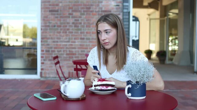 Woman on diet hesitates over eating a slice of cake at outdoor cafe struggling between sweet temptation calorie control healthy goals and personal cravings and discipline