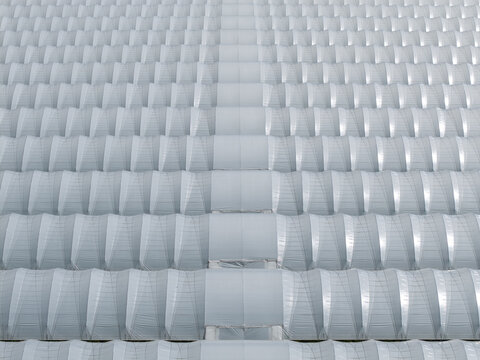 Aerial view of horticultural foil tunnels arranged in parallel rows forming a large greenhouse complex in Poland.